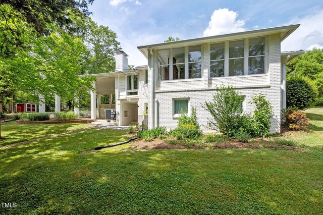 rear view of property featuring a lawn, brick siding, and a chimney