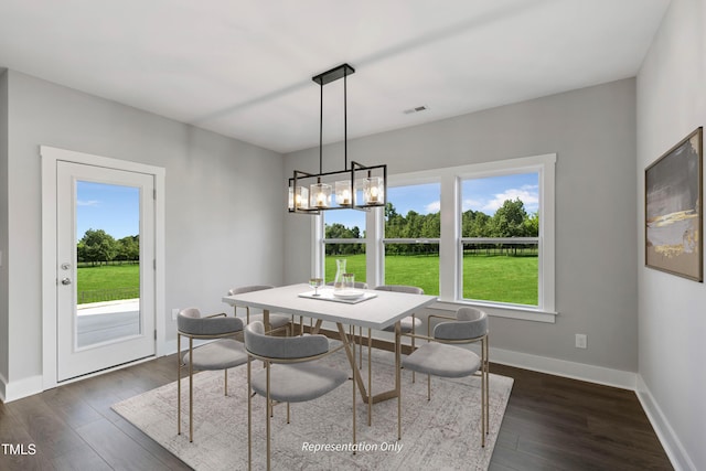 dining area with healthy amount of natural light, dark wood-style floors, baseboards, and a chandelier
