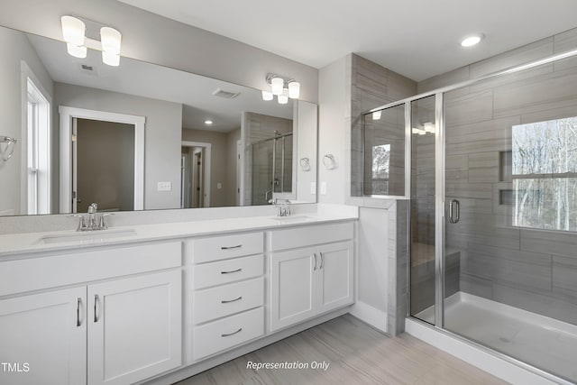 bathroom with a stall shower, double vanity, plenty of natural light, and recessed lighting