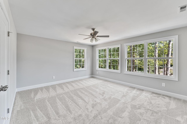 empty room with carpet flooring, ceiling fan, visible vents, and a healthy amount of sunlight