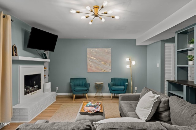 living area featuring a fireplace, a notable chandelier, wood finished floors, and baseboards