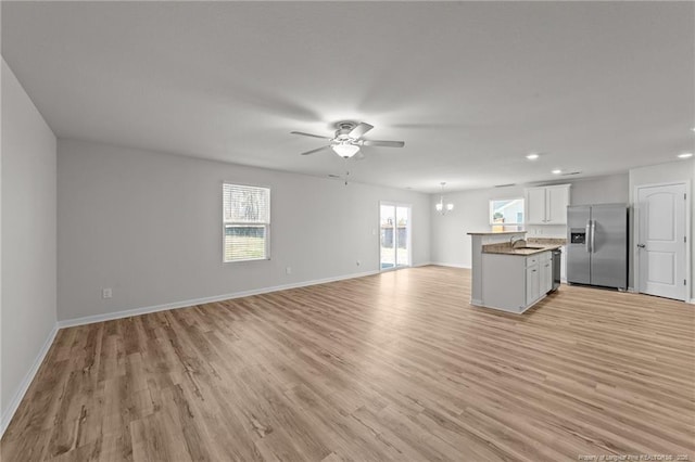 524 Mineral Spring Ln, Fuquay Varina, NC 27526 - unfurnished living room featuring baseboards, light wood-type flooring, ceiling fan with notable chandelier, and a sink