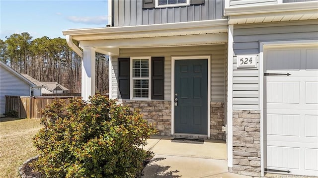 524 Mineral Spring Ln, Fuquay Varina, NC 27526 - entrance to property featuring stone siding, fence, board and batten siding, a garage, and a porch