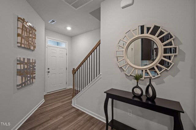 foyer entrance with wood finished floors, baseboards, and stairs