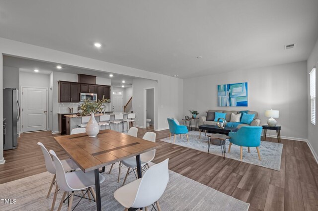 dining area with light wood-style flooring, stairway, baseboards, and recessed lighting