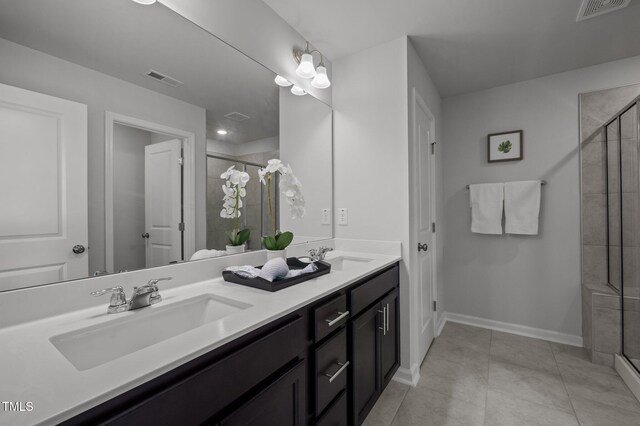 bathroom featuring a shower stall, double vanity, baseboards, and tile patterned flooring