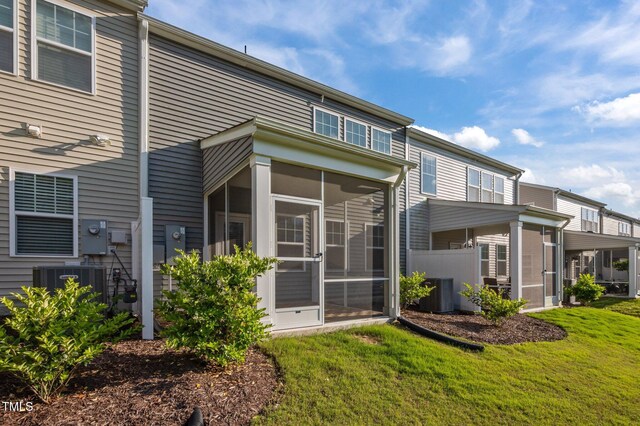 back of house with a sunroom, central AC, and a lawn