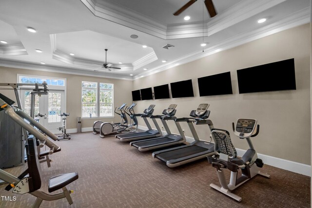 exercise room featuring ceiling fan, baseboards, a raised ceiling, carpet flooring, and ornamental molding