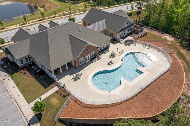 aerial view of property and surrounding area featuring a pool and a large body of water
