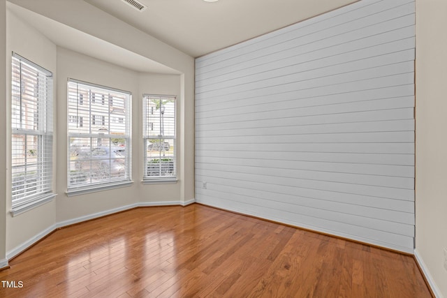 unfurnished room featuring baseboards, light wood finished floors, and visible vents