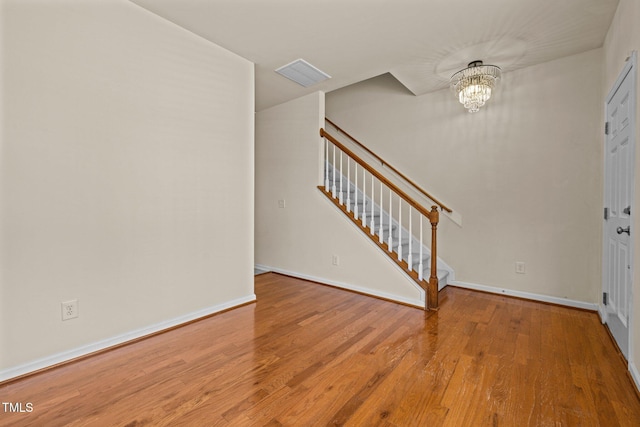 entryway with stairs, baseboards, a notable chandelier, and wood finished floors