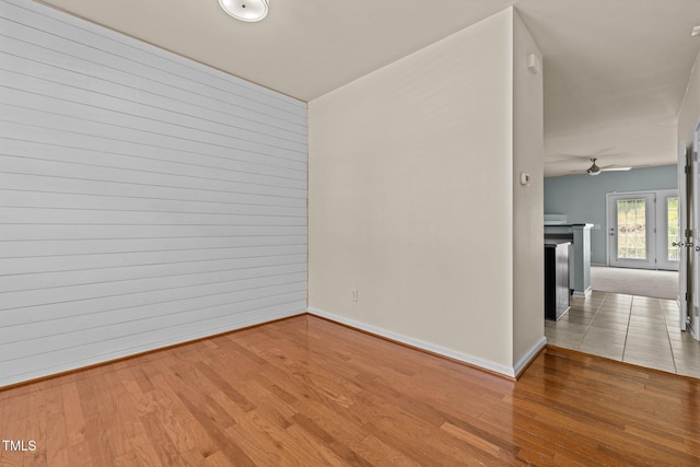spare room with a ceiling fan, baseboards, and wood finished floors