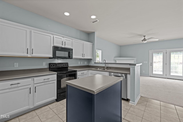 kitchen with visible vents, a sink, light tile patterned floors, white cabinets, and black appliances