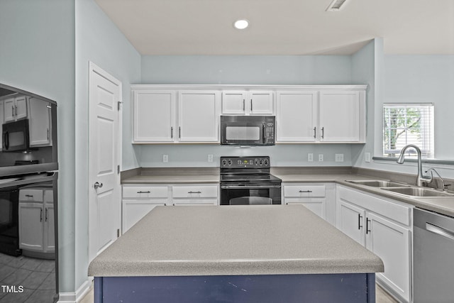 kitchen with white cabinets, a sink, light countertops, a center island, and black appliances