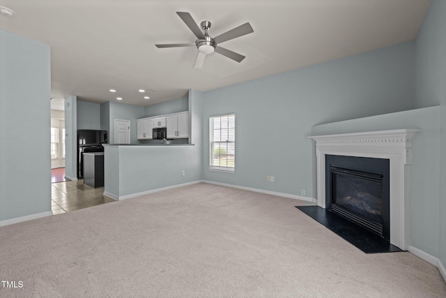 unfurnished living room featuring baseboards, a ceiling fan, a fireplace with flush hearth, and light carpet