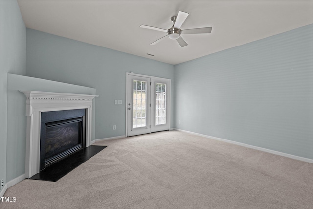 unfurnished living room with carpet floors, a ceiling fan, baseboards, and a fireplace with flush hearth