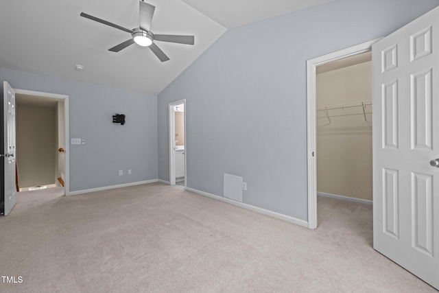 unfurnished bedroom with a closet, lofted ceiling, baseboards, a spacious closet, and carpet flooring