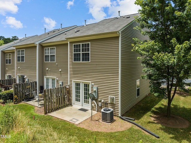 back of property featuring fence, cooling unit, a shingled roof, a patio area, and a lawn