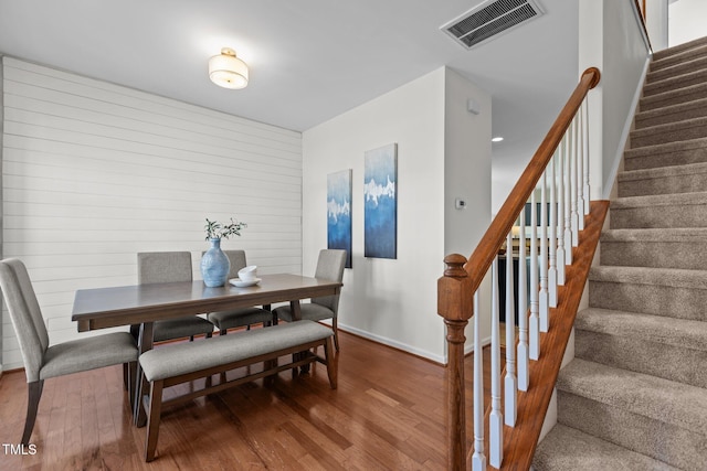 2713 Wyntercrest Ln, Durham, NC 27713 - dining area featuring wood walls, baseboards, wood finished floors, visible vents, and stairway