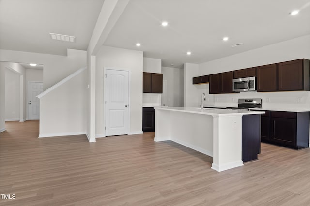 4867 Pioneer Dr, Sanford, NC 27330 - kitchen with an island with sink, visible vents, light countertops, stainless steel appliances, and light wood finished floors