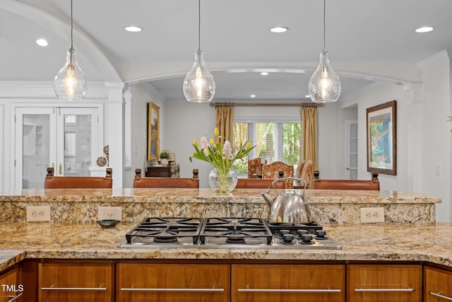 3915 Nottaway Rd, Durham, NC 27707 - kitchen featuring stainless steel gas stovetop, brown cabinetry, light stone countertops, recessed lighting, and decorative light fixtures