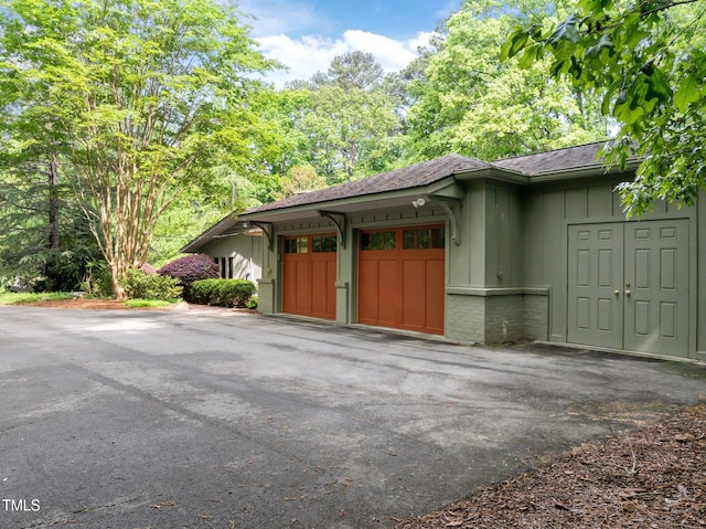 3915 Nottaway Rd, Durham, NC 27707 - view of property exterior with board and batten siding, a garage, asphalt driveway, a shingled roof, and brick siding