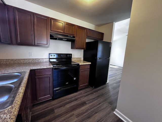 kitchen featuring under cabinet range hood, dark wood-type flooring, black appliances, and a sink