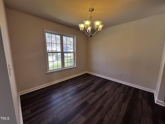 empty room with a chandelier, visible vents, dark wood finished floors, and baseboards