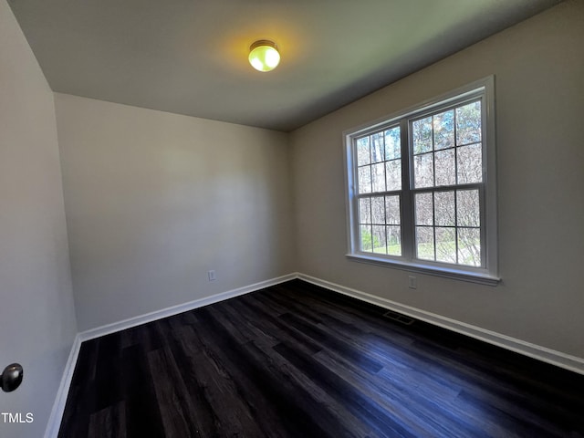 spare room featuring dark wood finished floors and baseboards