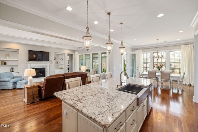 301 Rocking Ranch Ct, Cary, NC 27519 - kitchen featuring open floor plan, dark wood finished floors, a kitchen island with sink, a fireplace, and pendant lighting