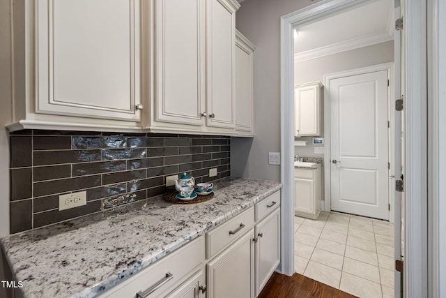 301 Rocking Ranch Ct, Cary, NC 27519 - kitchen featuring crown molding, backsplash, light stone countertops, and white cabinetry