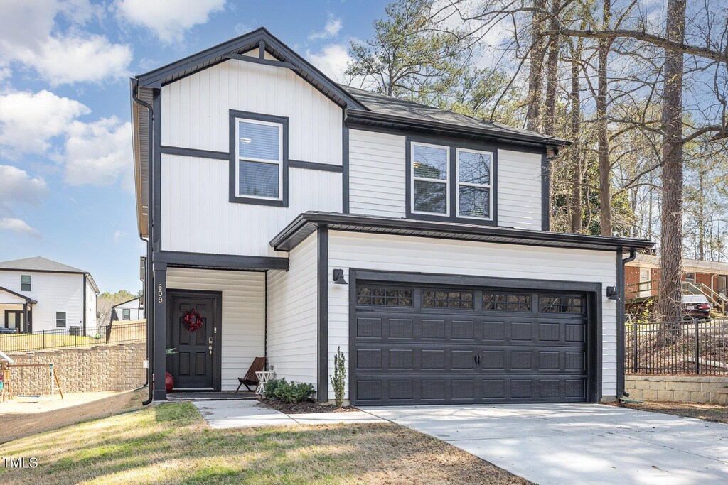 view of front of house featuring driveway, an attached garage, and fence