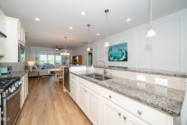 kitchen featuring light wood-style floors, white cabinetry, a sink, backsplash, and stainless steel appliances