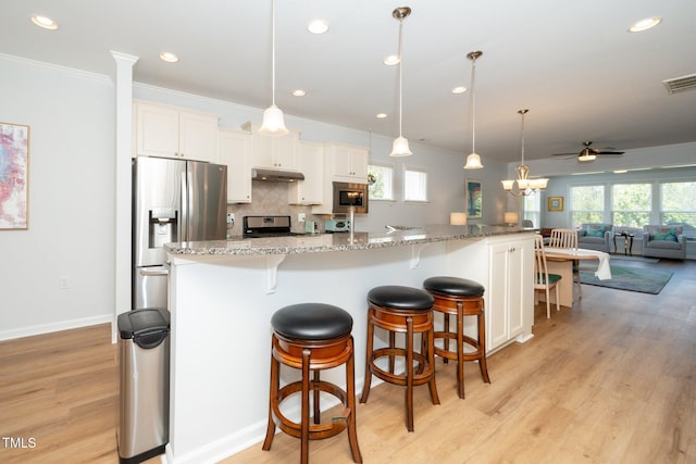 kitchen featuring appliances with stainless steel finishes, ornamental molding, under cabinet range hood, and a wealth of natural light