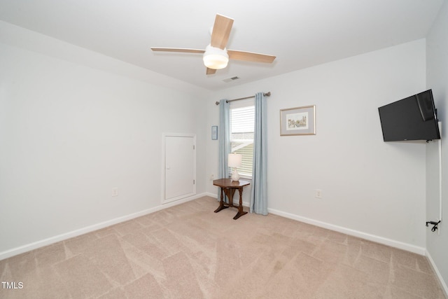 spare room with baseboards, visible vents, light carpet, and ceiling fan