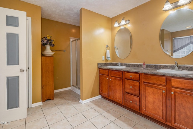 8404 Frenchorn Ln, Fayetteville, NC 28314 - bathroom with tile patterned flooring, a shower stall, double vanity, a textured ceiling, and a sink
