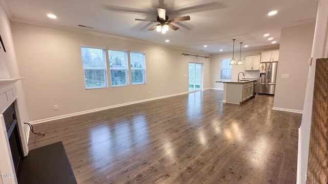 49 W Copenhaver Dr, Clayton, NC 27527 - unfurnished living room with ceiling fan, a fireplace with flush hearth, recessed lighting, crown molding, and a sink