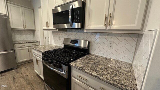 49 W Copenhaver Dr, Clayton, NC 27527 - kitchen with appliances with stainless steel finishes, dark wood-type flooring, light stone countertops, tasteful backsplash, and white cabinets