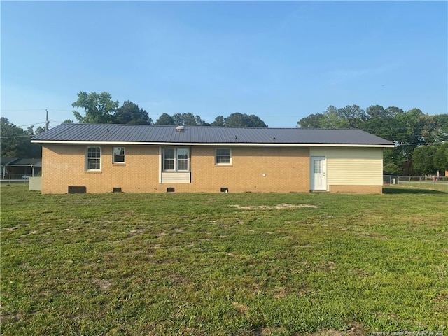 back of property with crawl space, metal roof, a yard, and brick siding