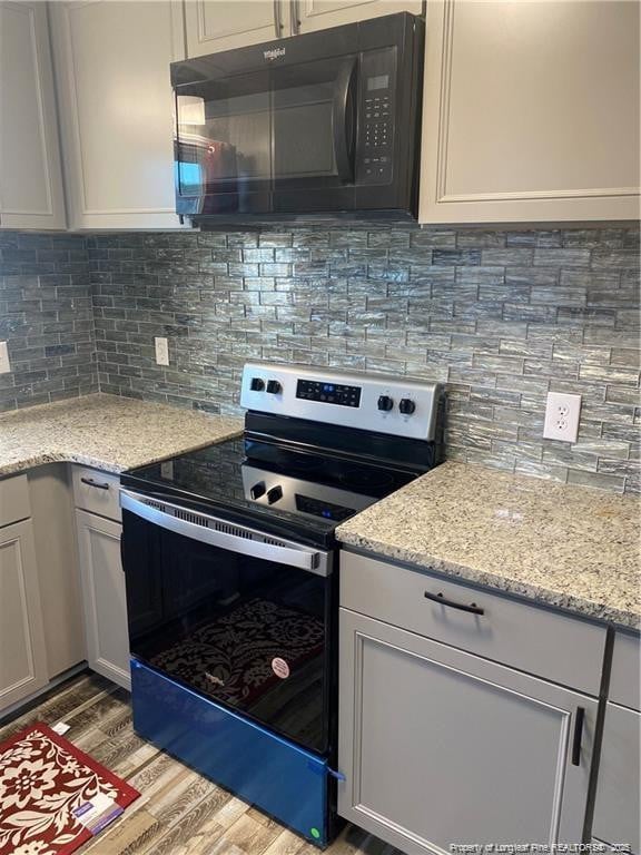 kitchen with backsplash, light wood-type flooring, stainless steel electric stove, and black microwave