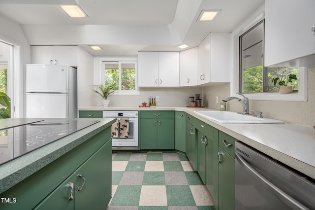 kitchen featuring white appliances, light floors, light countertops, green cabinetry, and a sink