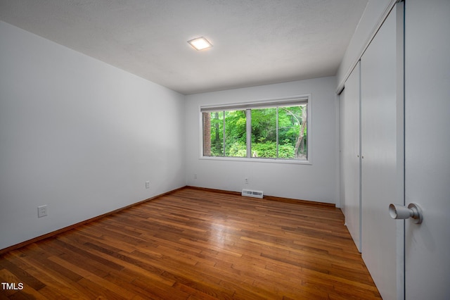 unfurnished bedroom featuring baseboards, wood-type flooring, and visible vents