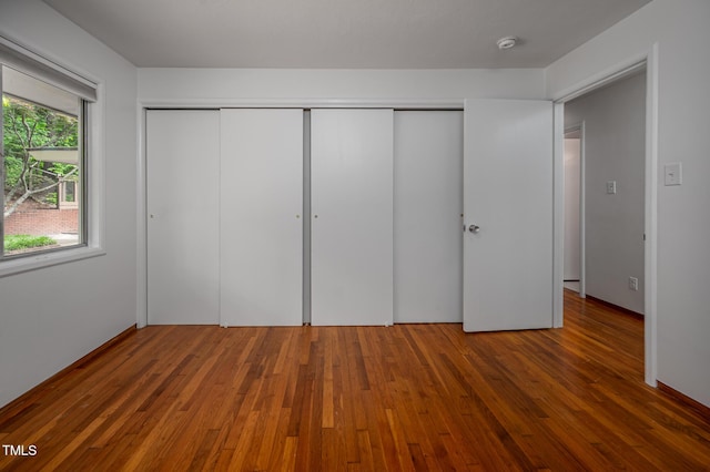 unfurnished bedroom featuring a closet and hardwood / wood-style flooring