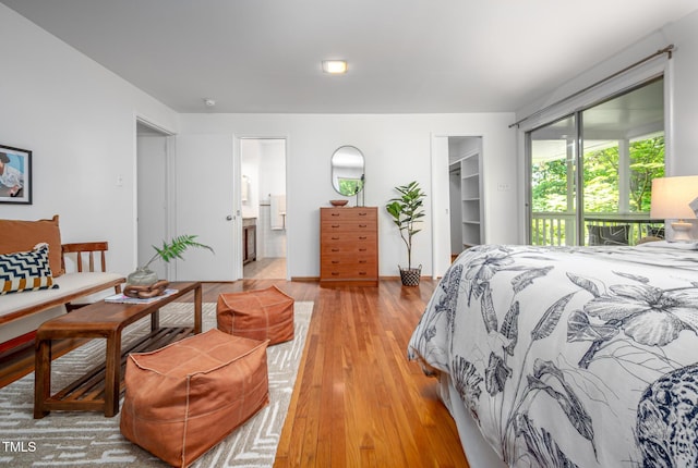 bedroom featuring a closet, light wood-type flooring, ensuite bath, and a spacious closet