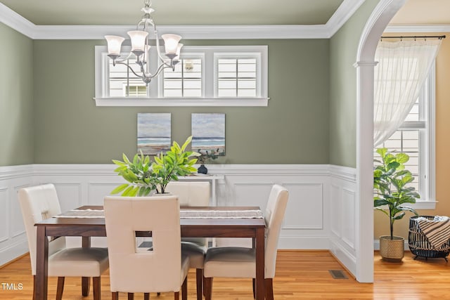 5233 Greymoss Ln, Apex, NC 27539 - dining area with a chandelier, light wood-style flooring, crown molding, a wainscoted wall, and a decorative wall