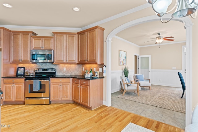 5233 Greymoss Ln, Apex, NC 27539 - kitchen featuring stainless steel appliances, ceiling fan, light wood finished floors, crown molding, and arched walkways