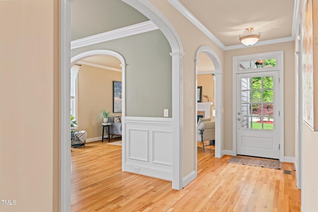 5233 Greymoss Ln, Apex, NC 27539 - foyer featuring arched walkways, light wood-type flooring, ornamental molding, a fireplace, and ornate columns