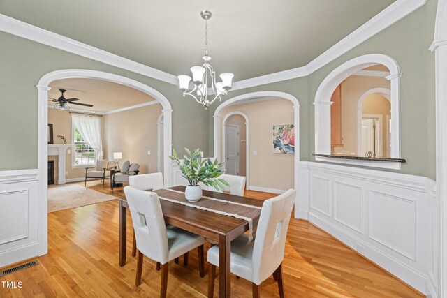 5233 Greymoss Ln, Apex, NC 27539 - dining room with a fireplace, crown molding, light wood finished floors, arched walkways, and ceiling fan