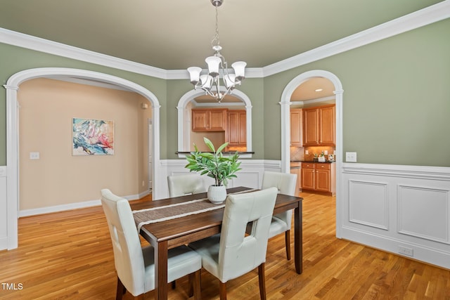 5233 Greymoss Ln, Apex, NC 27539 - dining room featuring a chandelier, arched walkways, light wood-style floors, and crown molding