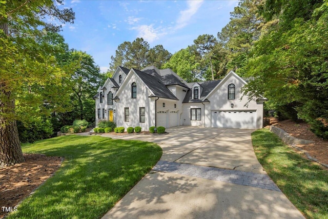 1508 Tradescant Ct, Raleigh, NC 27613 - french country home featuring stucco siding, a front yard, driveway, and view of scattered trees